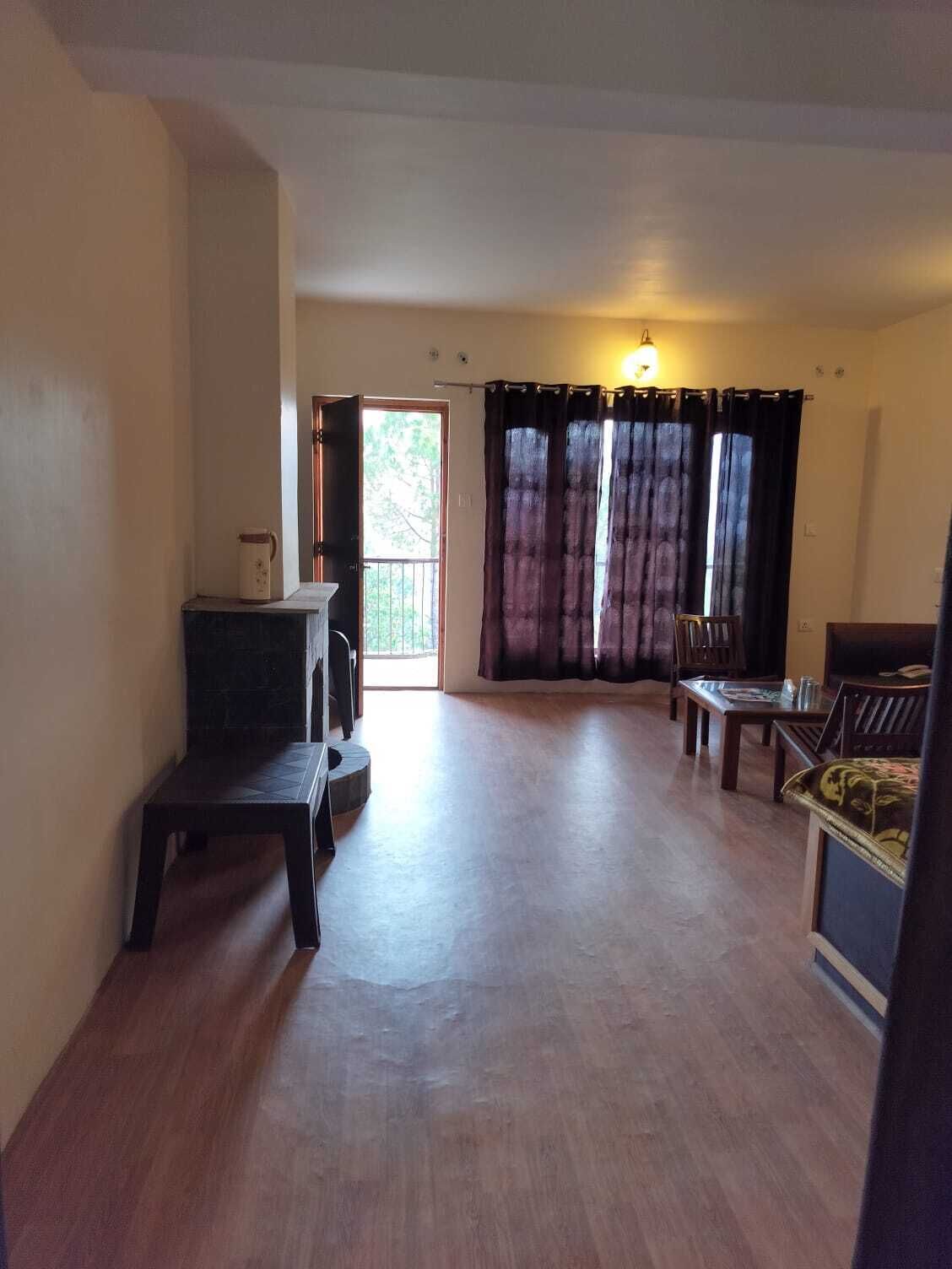 Amplia sala de estar con piso de madera, una mesa de comedor, un sofá y una mesita con una jarra.