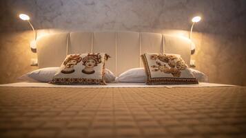 A bed with two decorative pillows, a headboard, and two wall-mounted lamps.