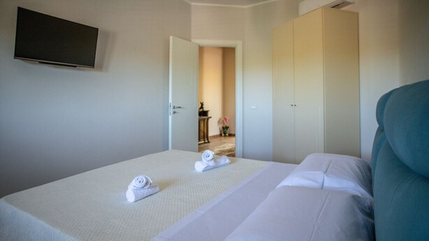 A hotel room with a bed, a TV mounted on the wall, and a wardrobe. - La Dolce Vita - Palermo (Palermo)