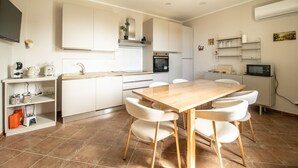 A modern kitchen with white cabinetry, a wooden dining table, and chairs. - La Dolce Vita - Palermo (Palermo)