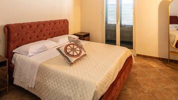 A bedroom with a large bed, a red upholstered headboard, a ceiling with frescoes, and a sliding glass door.
