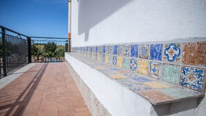 A tiled outdoor walkway adjacent to a white wall with a black metal railing. - La Dolce Vita - Palermo (Palermo)