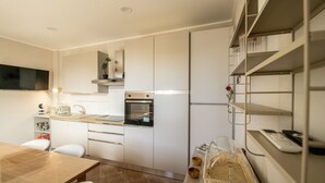 A compact kitchen with white cabinets, a built-in oven, a sink, and a dining area with a table and chairs. - La Dolce Vita - Palermo (Palermo)