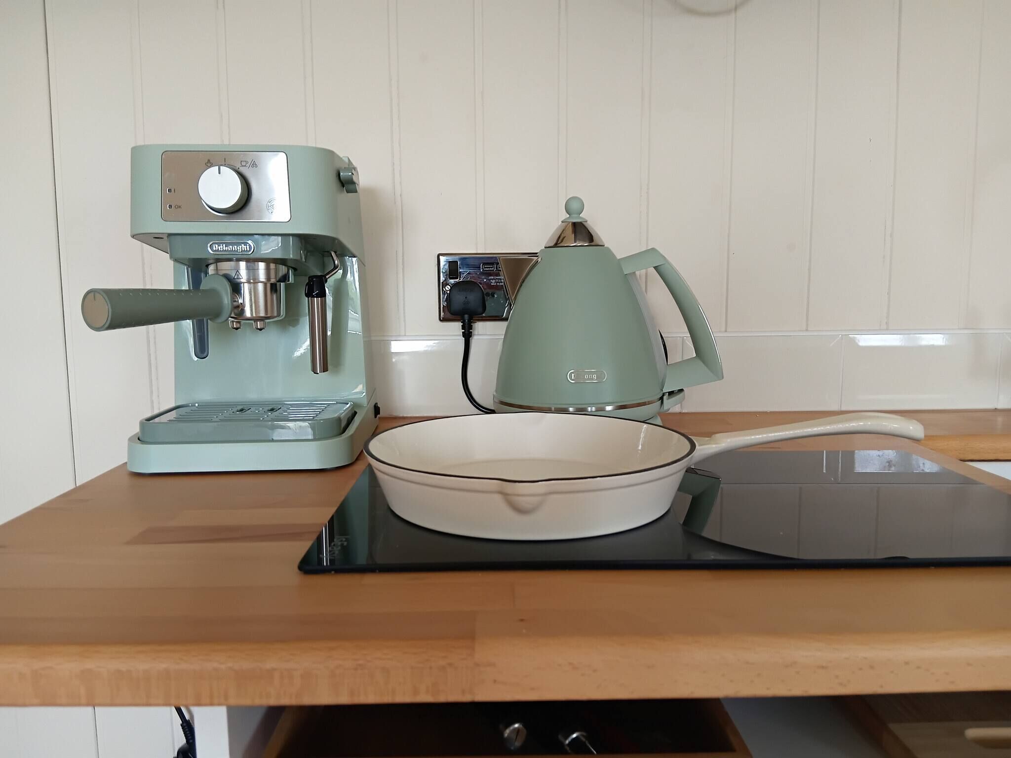 A kitchen with a coffee maker, a kettle, and a bowl on the counter.
