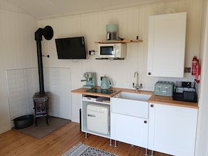 Una cocina compacta equipada con microondas, cafetera, tostadora y un refrigerador pequeño.