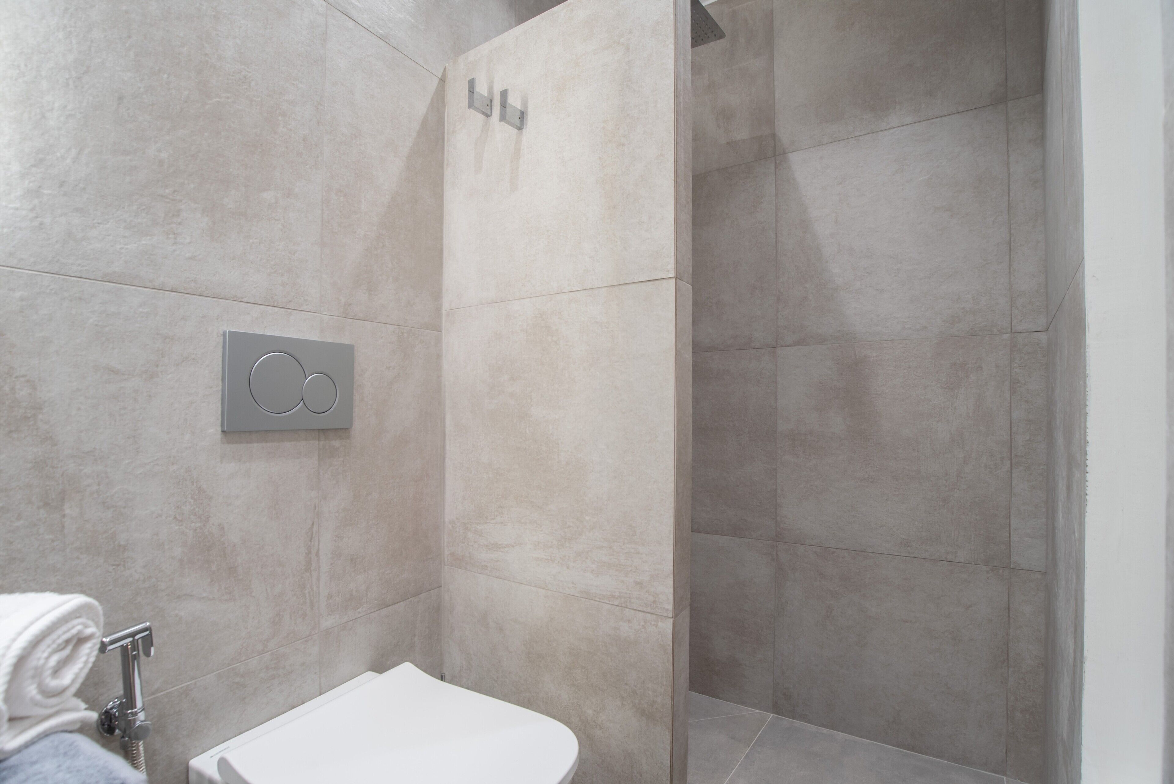 Une salle de bain moderne équipée d’une douche, de toilettes et d’un porte-serviettes.