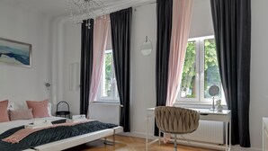 A bedroom with a bed, a desk, a chair, a radiator, and a window with curtains. - Parkowa 19 - Beach & Chill Sopot (Sopot)