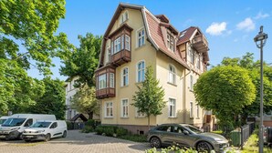 A multi-story residential building with a traditional architectural style, featuring a balcony on the second floor and a driveway with parked vehicles. - Parkowa 19 - Beach & Chill Sopot (Sopot)