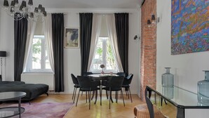 A modern living room with a dining area, a chandelier, and a large window with curtains. - Parkowa 19 - Beach & Chill Sopot (Sopot)