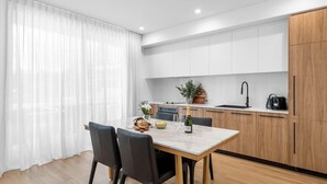Eine moderne Küche mit weißen Schränken, einem Holztisch und Stühlen.