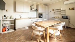 Una cocina moderna con armarios blancos, una mesa de comedor de madera y seis sillas.