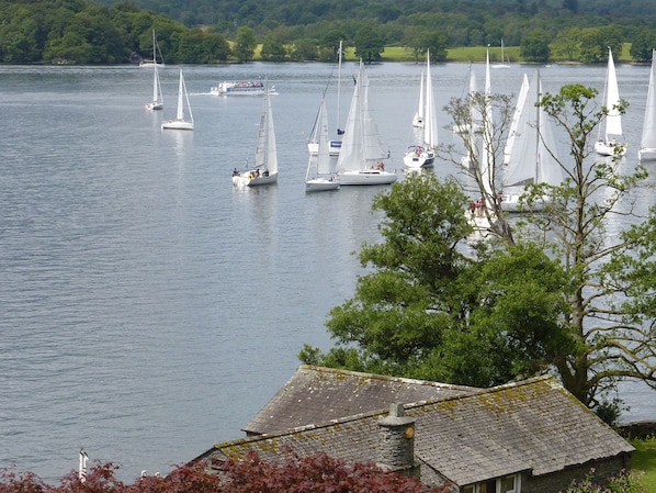 A lake with sailboats, a stone building with a thatched roof, and a tree in the foreground. - Romantic Boathouse on Lake Windermere (Windermere)