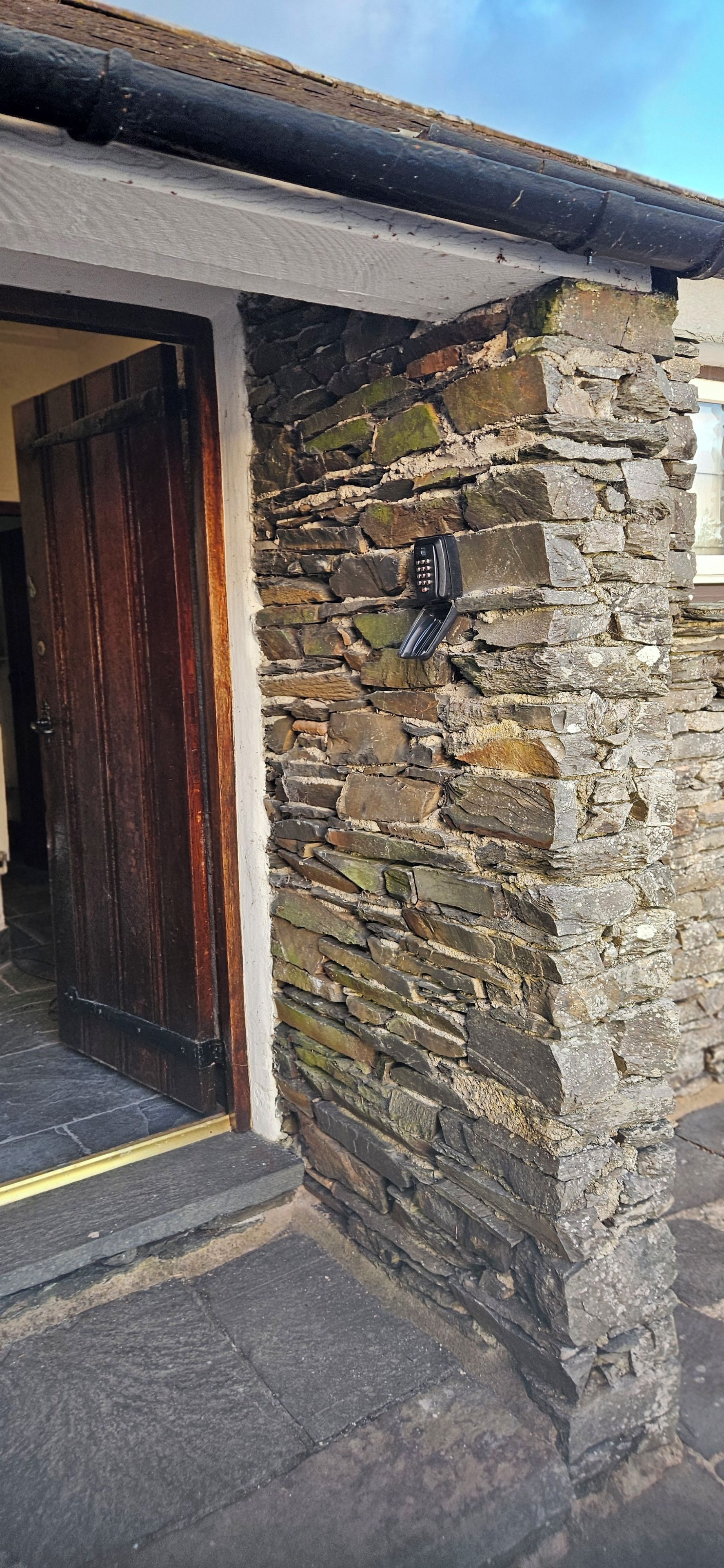 A stone wall with a door and a mailbox.