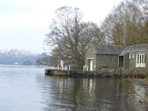 A stone building by a calm lake with a distant mountain and a leafless tree. - Romantic Boathouse on Lake Windermere (Windermere)