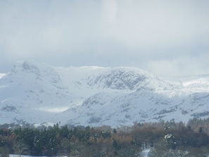 A snow-covered mountain range with a forested valley in the foreground. - Romantic Boathouse on Lake Windermere (Windermere)