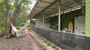 A covered outdoor area with a hammock, a surfboard, and a green wall. - Cozy forest home one block from renowned Playa Grande surfing beach (Playa Grande)