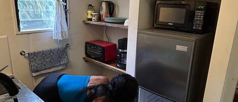 A compact kitchen with a stainless steel sink, a microwave, and a refrigerator.
