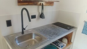 Een kleine keuken met een roestvrijstalen spoelbak, een zwarte kraan en een ingebouwde kookplaat.