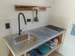 A compact kitchen with a stainless steel sink, a black faucet, and a built-in stove. - Cozy forest home one block from renowned Playa Grande surfing beach (Playa Grande)