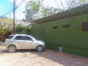 A car parked next to a green building with multiple windows. - Cozy forest home one block from renowned Playa Grande surfing beach (Playa Grande)