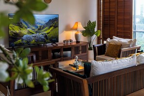 Ein Wohnzimmer mit Fernseher, Holzmöbeln, einer Lampe und einer Pflanze.