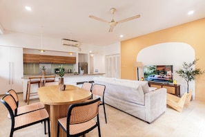 Un espacio habitable moderno con comedor, sofá, televisor y cocina.