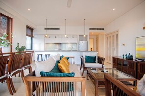Una sala moderna con un sofá, sillas, una mesa de centro y un televisor.
