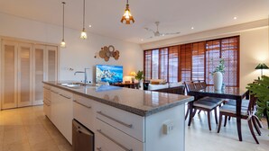 Une cuisine moderne dotée d’un îlot central, d’un coin repas avec des chaises en bois et d’un ventilateur de plafond.