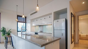 Une cuisine moderne dotée de plans de travail en granit, d’appareils électroménagers en acier inoxydable et de luminaires suspendus.