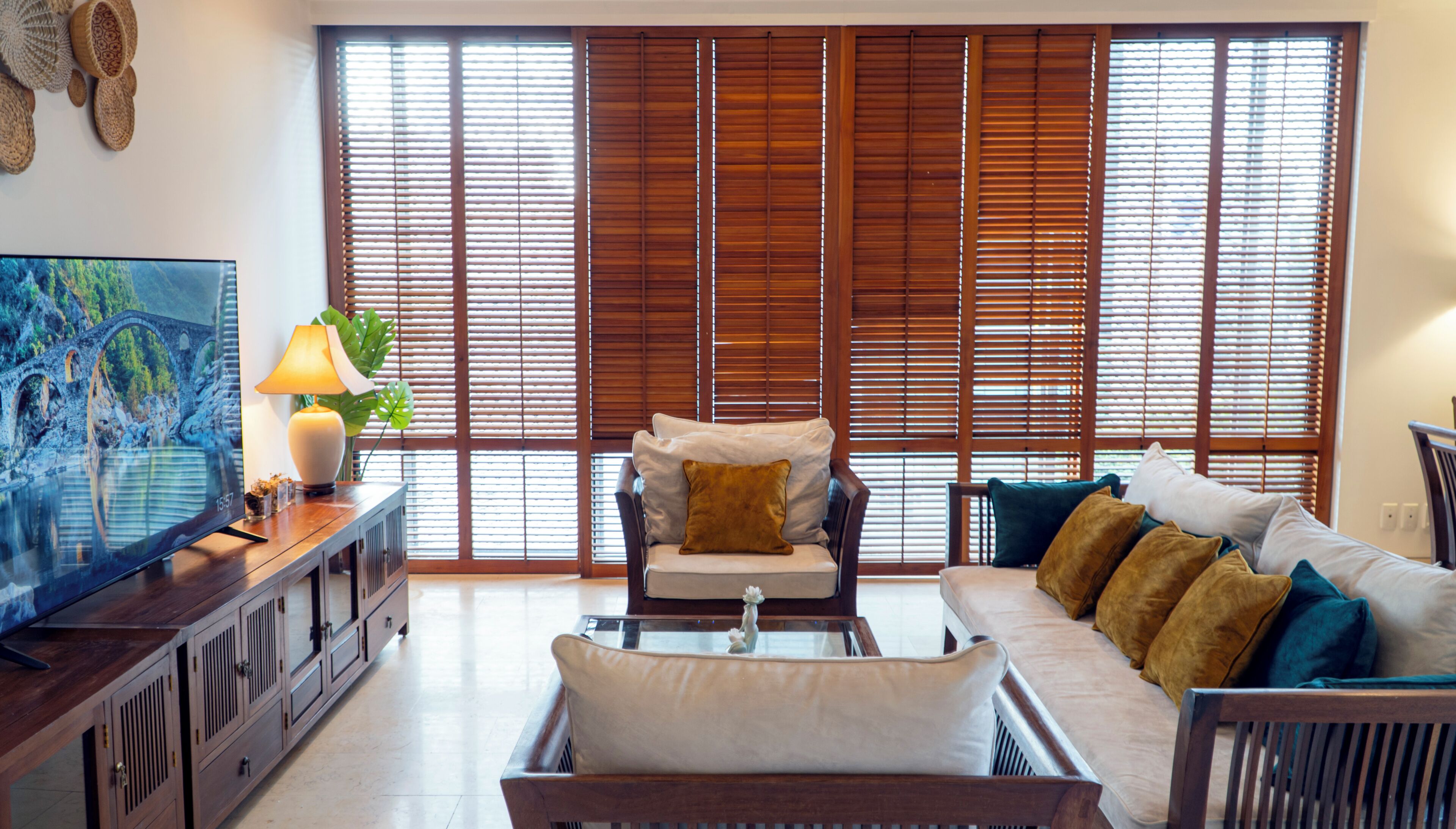 Una sala de estar con sofá, sillón, televisor y persianas de madera.
