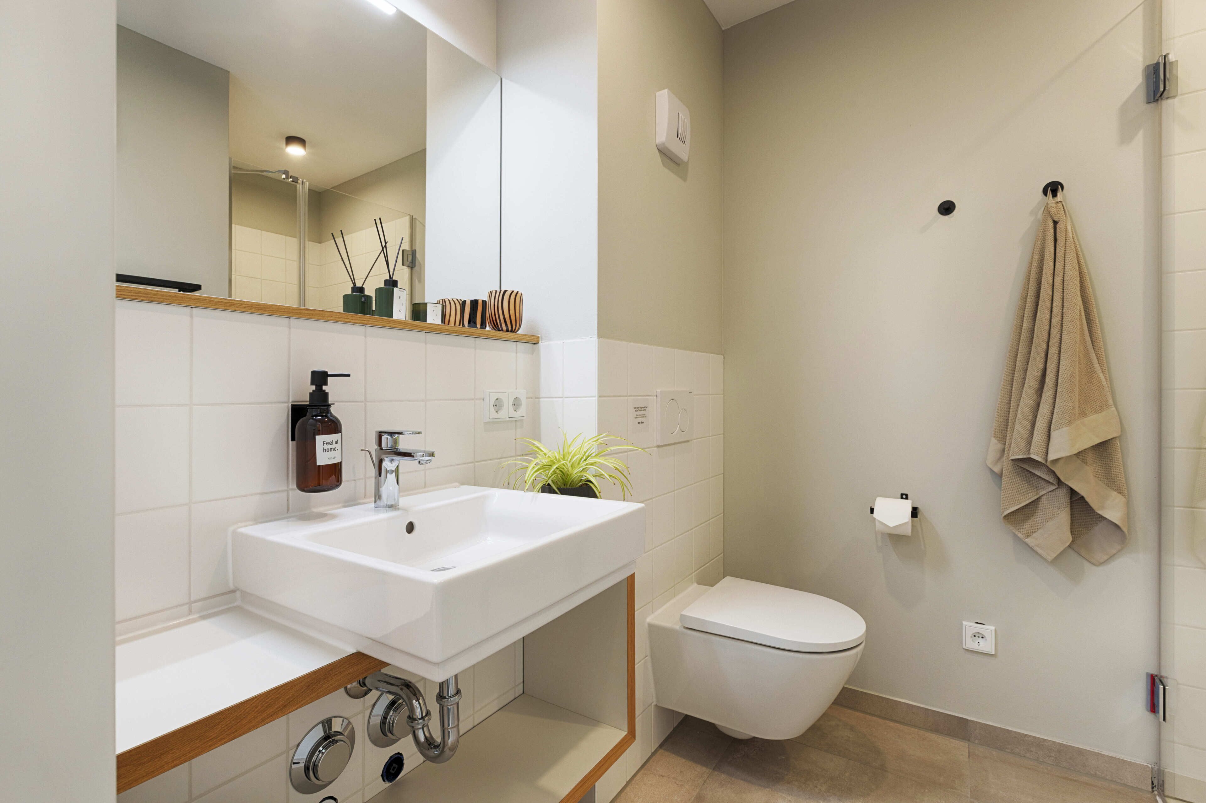 A modern bathroom with a white sink, toilet, and shower.