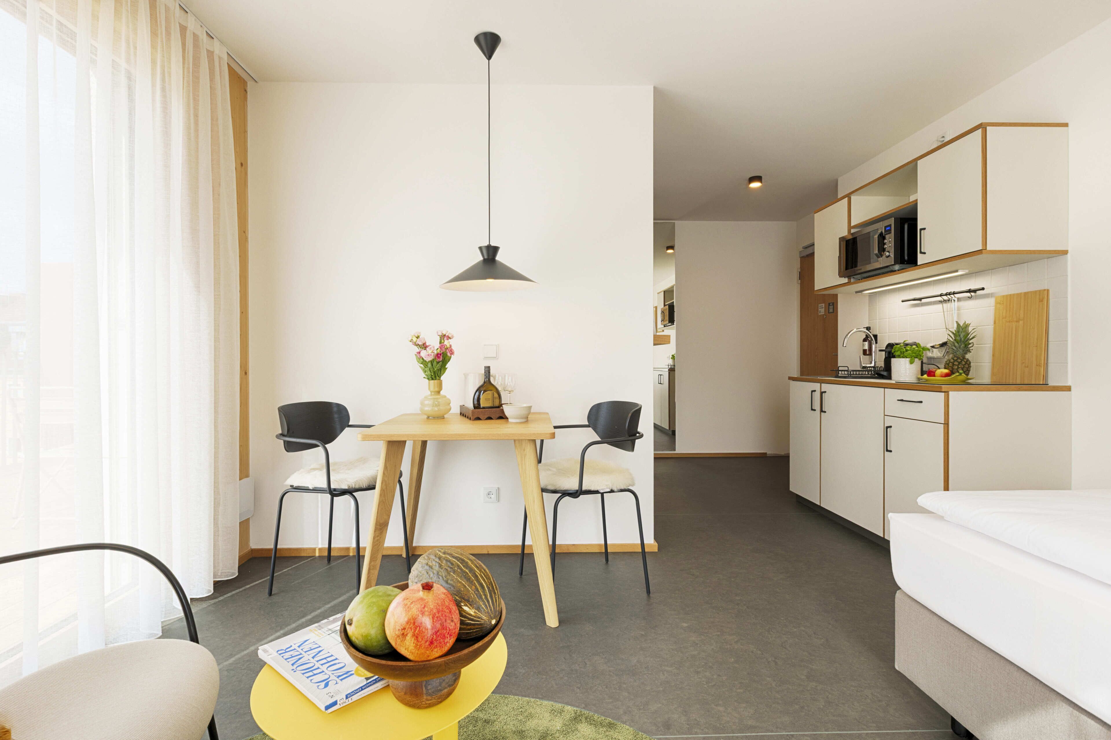 Une chambre d’hôtel moderne dotée d’un coin repas, d’une kitchenette et offrant une vue sur la ville.