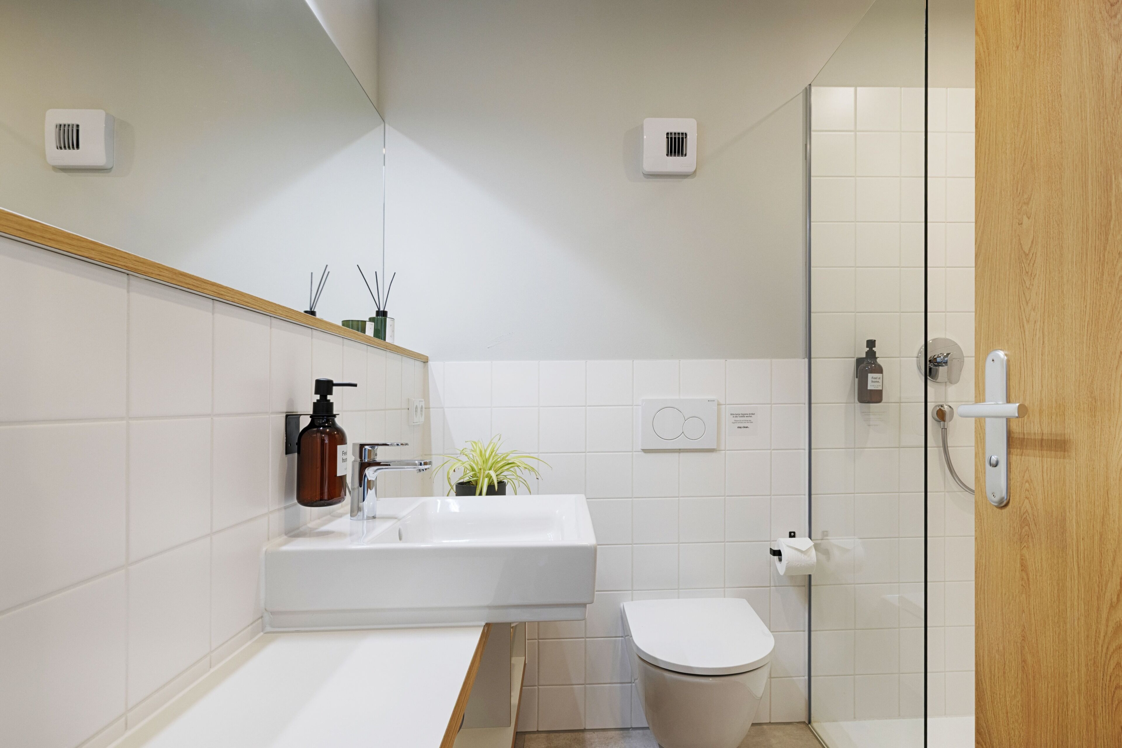 A modern bathroom with a white sink, toilet, and shower.