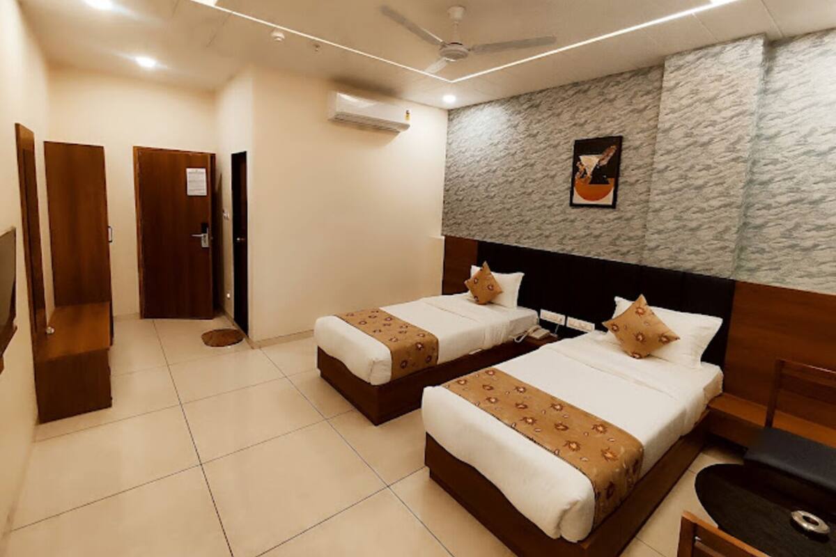 A hotel room with two beds, a ceiling fan, a wall-mounted air conditioner, and a framed picture.