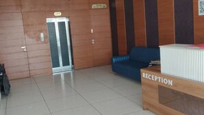 A reception area with a blue sofa, a reception desk labeled 'RECEPTION,' and a lift with a sign indicating 'BOOM5.'