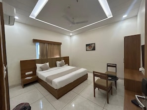 A modern hotel room with a large bed, a desk, and a chair.