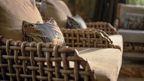 Wicker furniture with patterned cushions, a woven chair, and a sofa with a cushion.