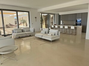 En moderne stue med sofa, et lille bord og et køkkenområde med bar og siddepladser.