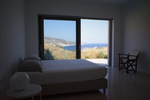 A bedroom with a large bed, a chair, and a view of the sea. - Laurentis Villa - Architect home with 180° sea views and a path to a wild beach (Chora)