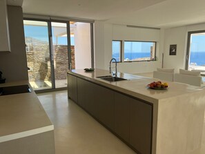 A modern kitchen with a large island, a sink, and a view of the sea. - Laurentis Villa - Architect home with 180° sea views and a path to a wild beach (Chora)