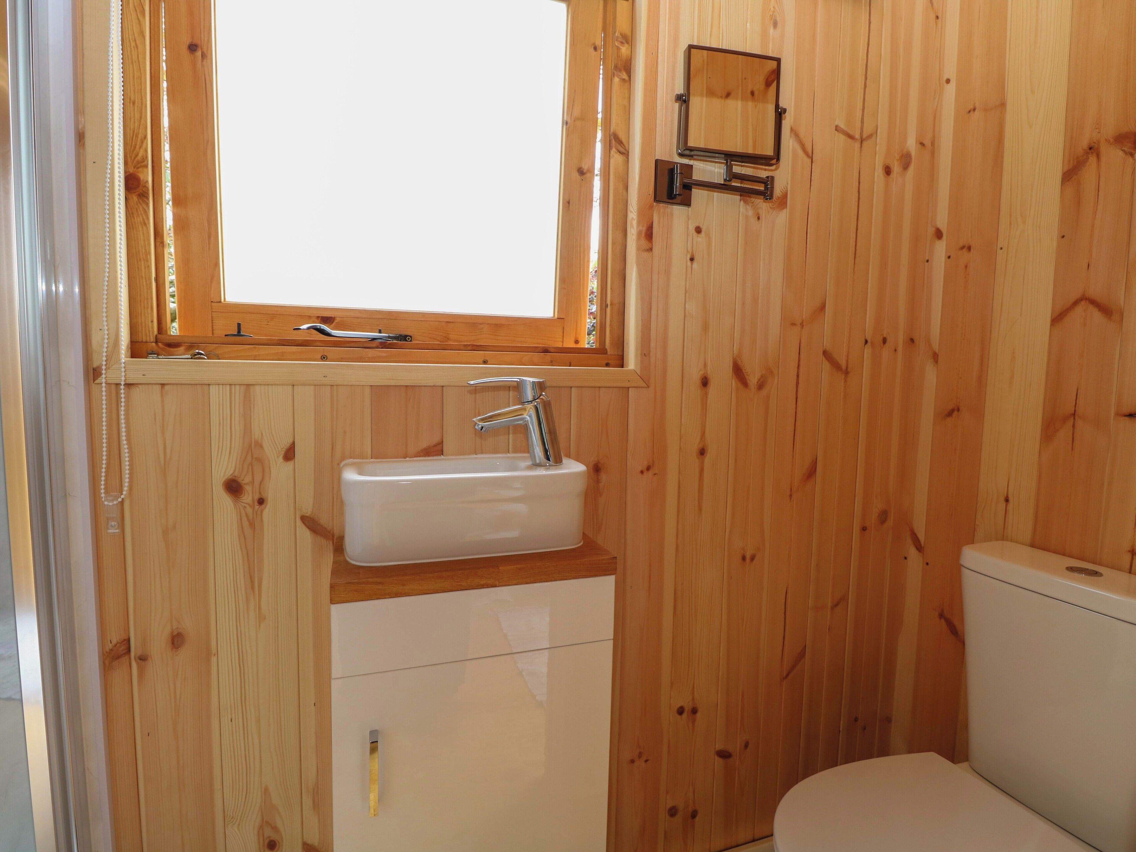A wooden bathroom with a window, sink, and toilet.