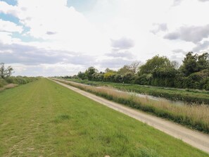 Ländliche Landschaft mit Feldwegen, Wiesen und einem Kanal.