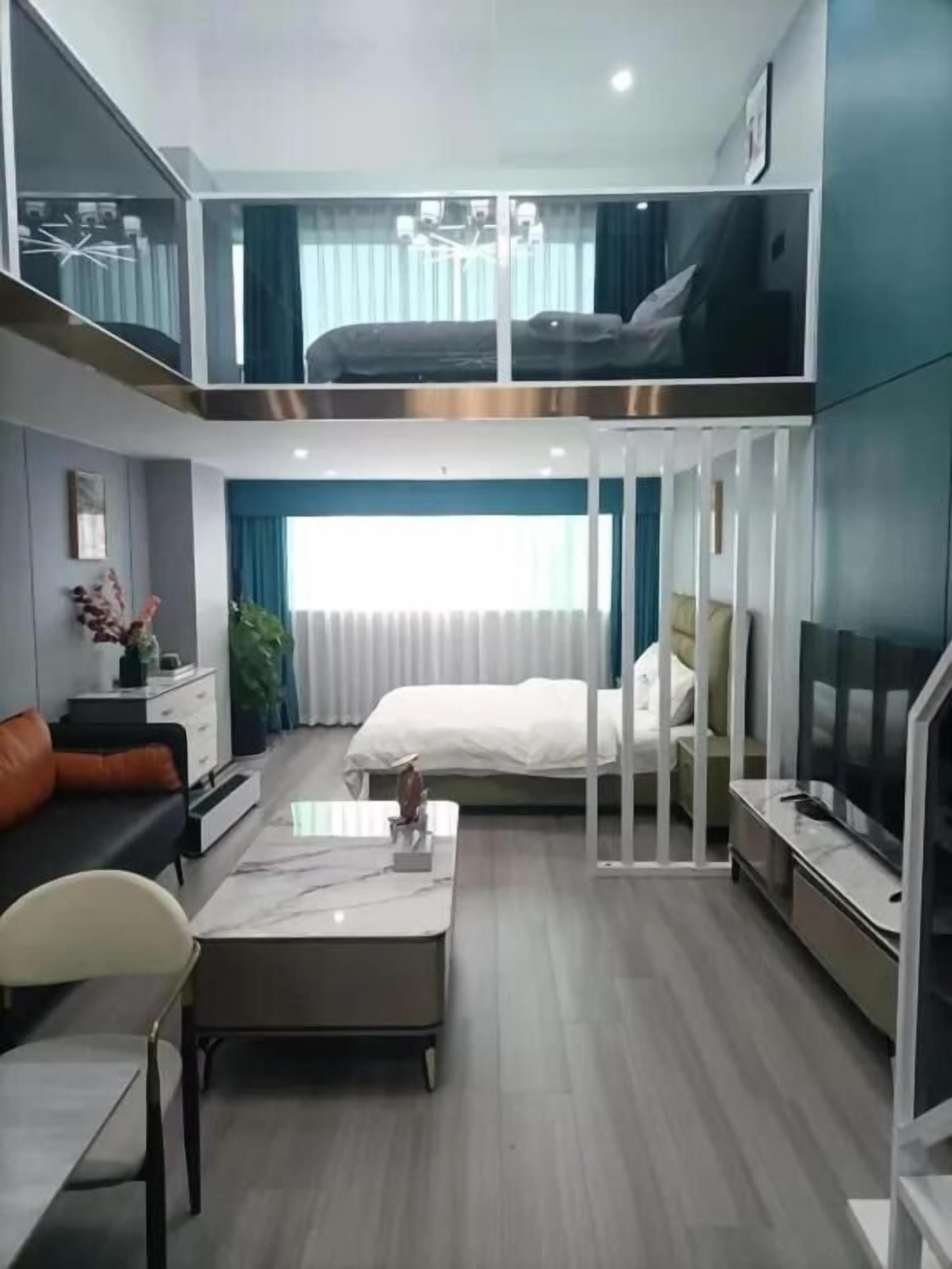 Una habitación de hotel moderna con cama estilo loft, zona de comedor y televisor.