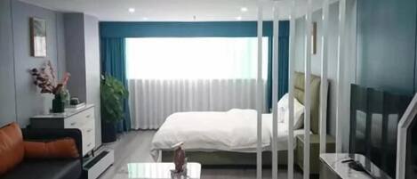 Una habitación de hotel moderna con cama estilo loft, zona de comedor y televisor.