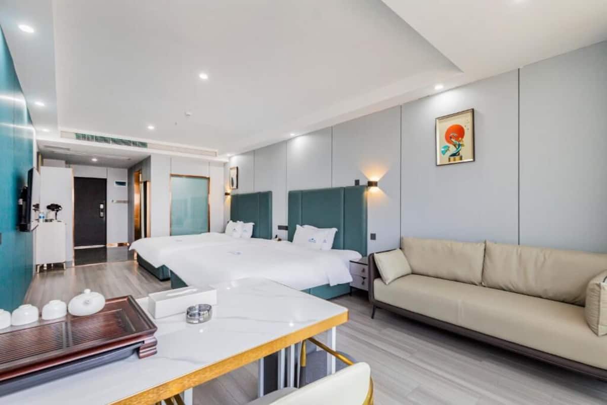 Habitación de hotel con una cama grande, un sofá, una mesa de comedor y una pequeña cocina.
