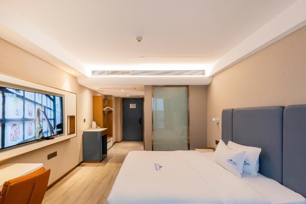 A hotel room with a bed, a TV, a desk, and a wardrobe.