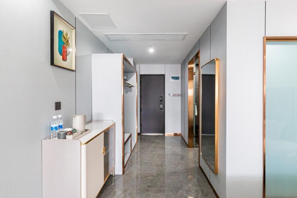 A hallway with a reception desk, water bottles, a framed picture, a door, and a mirror.