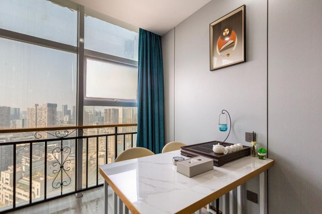 A room with a city view, a table with a tray, a framed picture, and a window with curtains.