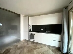Eine moderne Küche mit weißen Schränken, einer schwarzen Arbeitsplatte und einem eingebauten Backofen.