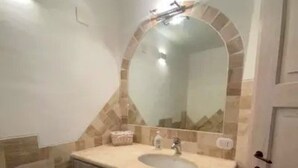 A bathroom with a sink, mirror, and tiled walls. - PRESTIGE SHERDEN (Golfo Aranci)